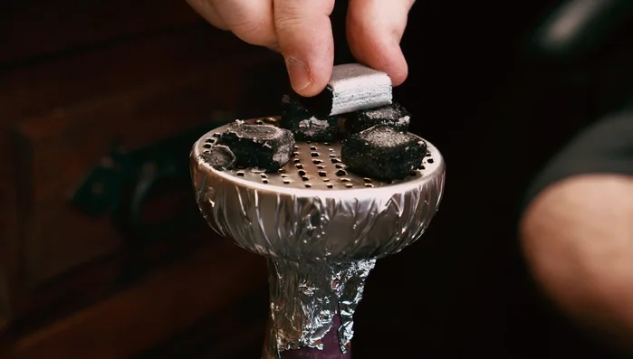 To light a new piece of charcoal, bridge it between two already lit pieces until it ignites.