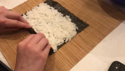 Continue rolling, using the bamboo mat for support. Wet the last edge of the paper to seal it.