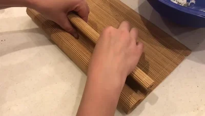 Continue rolling, using the bamboo mat for support. Wet the last edge of the paper to seal it.
