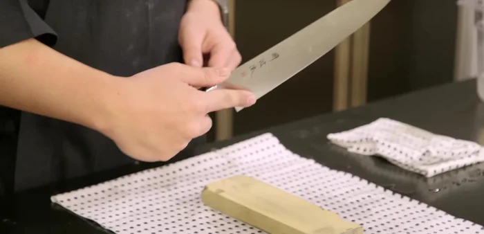 Sharpen the non-dominant side (backside): Hold the knife diagonally, using thumb on the spine and index finger on the heel. Apply pressure while pulling straight down, releasing pressure on the upward stroke. Work in sections.