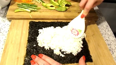 Add spicy mayo and desired fillings (cucumber, carrot, green onion, avocado) along the bottom edge of the rice.