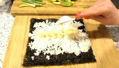 Add spicy mayo and desired fillings (cucumber, carrot, green onion, avocado) along the bottom edge of the rice.