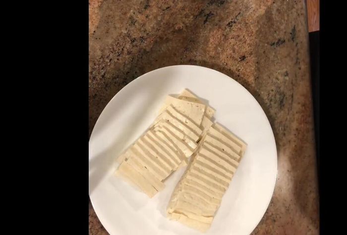 Arrange the tofu slices on a parchment-lined plate, leaving some space between them.