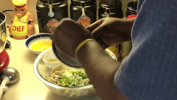 Add chopped onions (white and green), mayonnaise, Dijon mustard, lemon juice, eggs, and breadcrumbs to the flaked fish. Gently mix, adding more breadcrumbs if needed to bind the mixture.