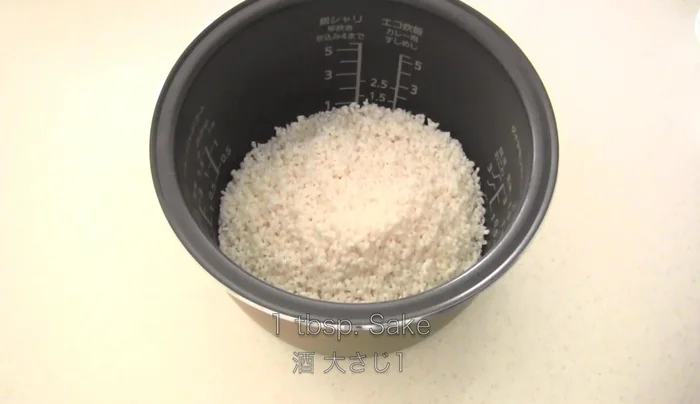 Place the seasoned mushrooms on top of the cooked rice in the rice cooker.