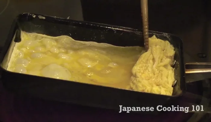 Wait until the egg sets slightly, then gently roll it into the previous layer.