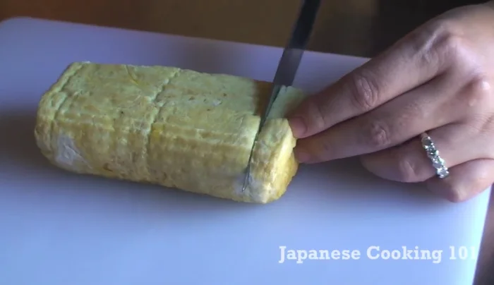 Unwrap and slice the dashimaki tamago into 1/2-inch thick pieces.