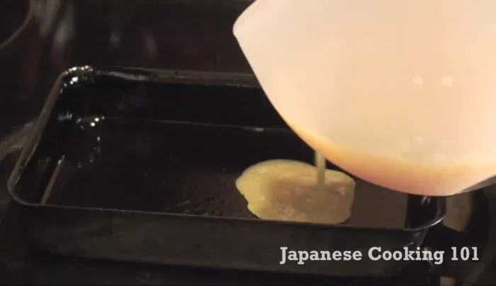Pour a thin layer of the egg mixture into the pan, tilting to coat the bottom.