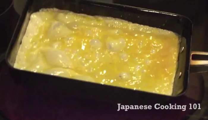 Once the egg begins to set (but before it's fully cooked), gently roll it towards one side of the pan.