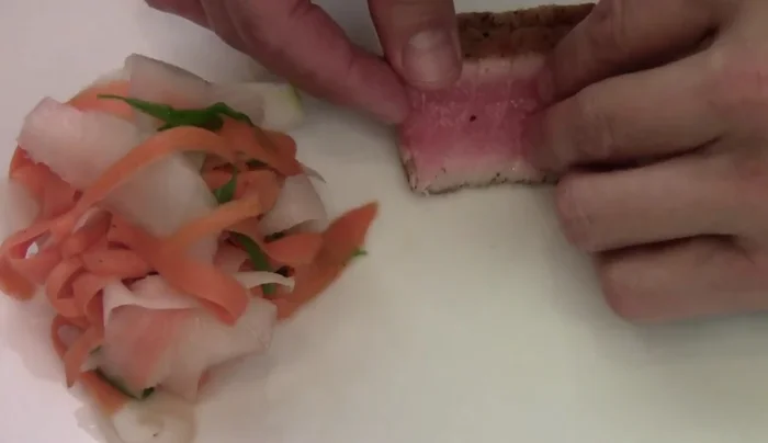Plate the tuna tataki. Arrange sliced tuna on a plate. Garnish with pickled vegetables, namami/shimi, e-sauce, sriracha, spicy mayo, and wasabi paste (optional).