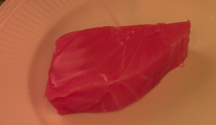 Drizzle olive oil on the tuna steak. Season generously with salt and pepper; add sesame seeds if desired.