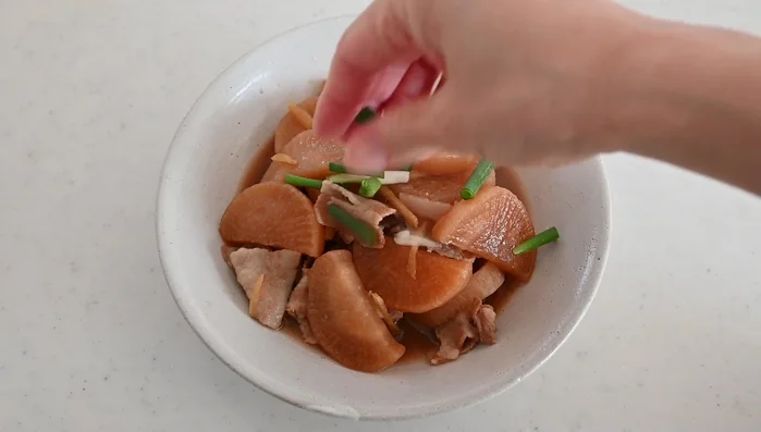 Transfer to a shallow bowl, top with scallions and shichimi chili pepper.
