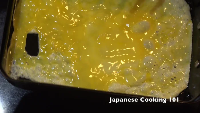 Gently roll the cooked egg to one side of the pan (forming a log).