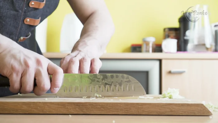 Person using Santoku knife for chopping