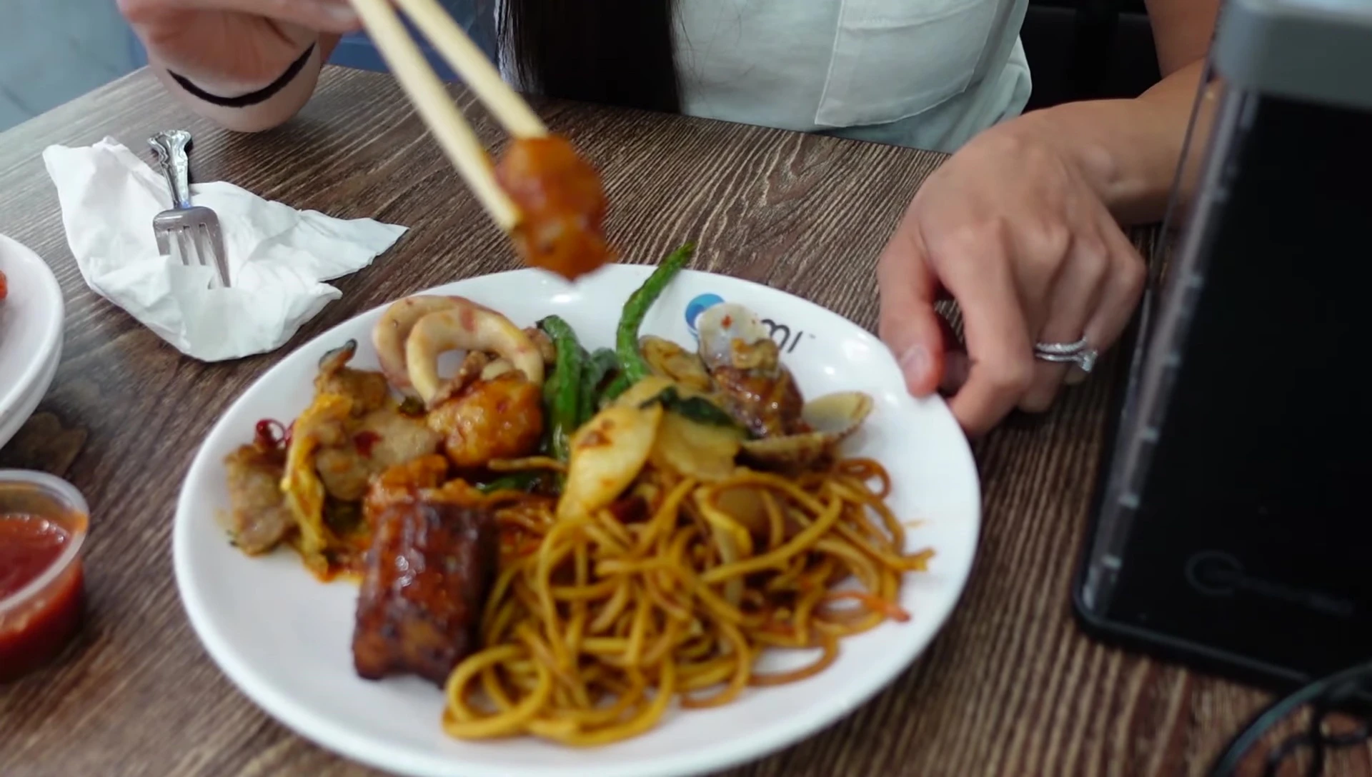 Person eating mixed seafood and noodle dish