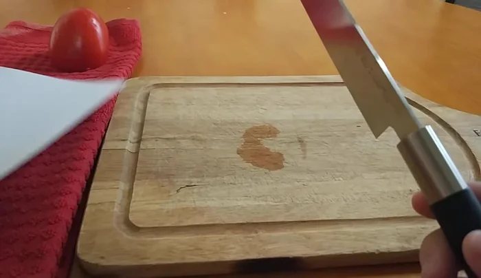 Sharp knife slicing through paper and tomato.