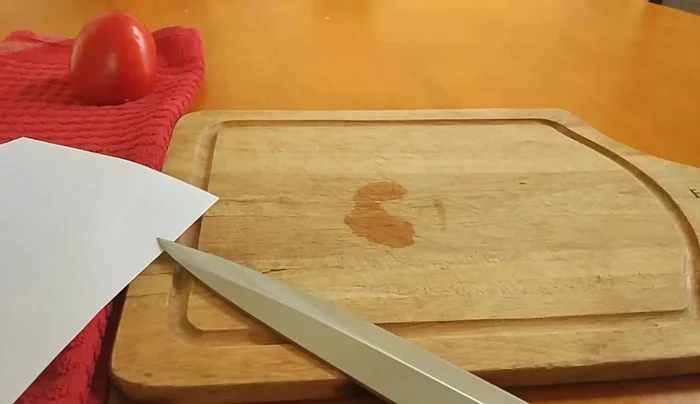 Sharp knife slicing paper and tomato.