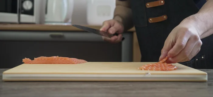 Yanagiba knife slicing salmon sashimi.