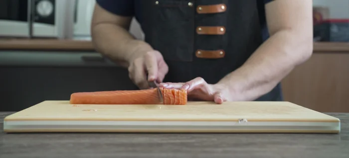 Yanagiba knife slicing salmon fillet.