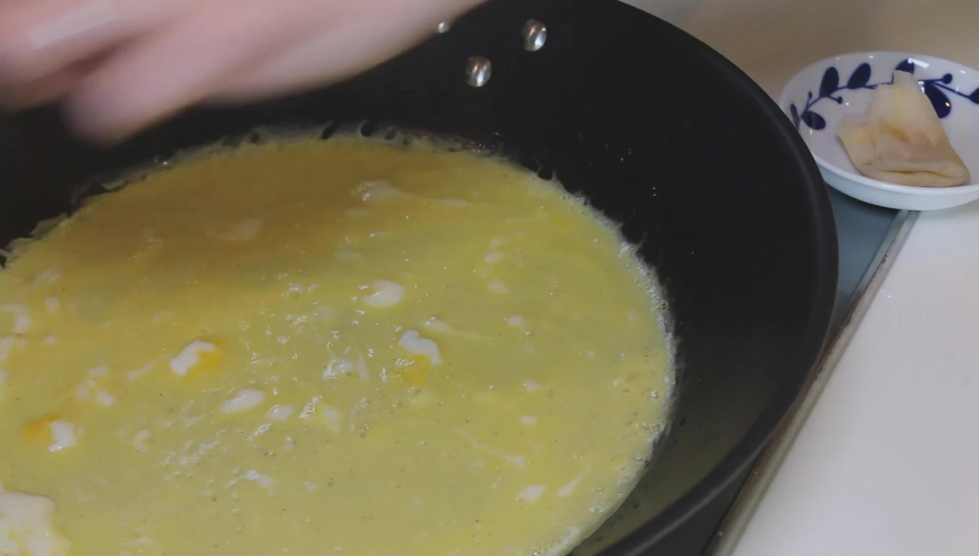 Cooking eggs in a pan, omelette in progress