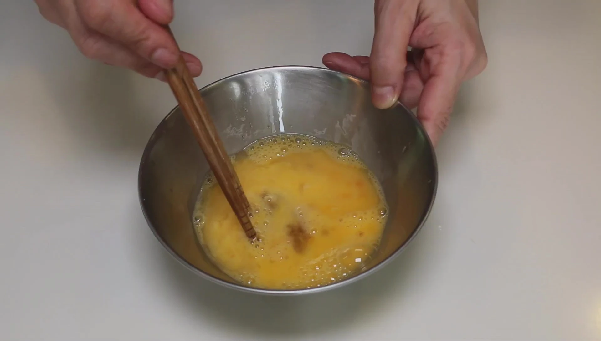 Adding seasoning to whisked eggs for tamagoyaki.