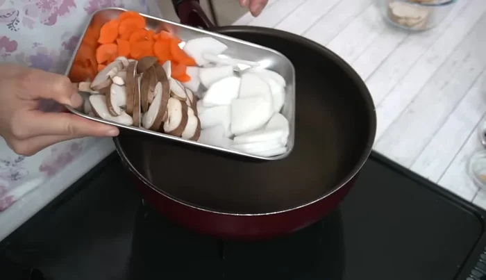 In a pot, combine daikon radish, carrots, and shiitake mushrooms with water. Bring to a boil over medium heat.