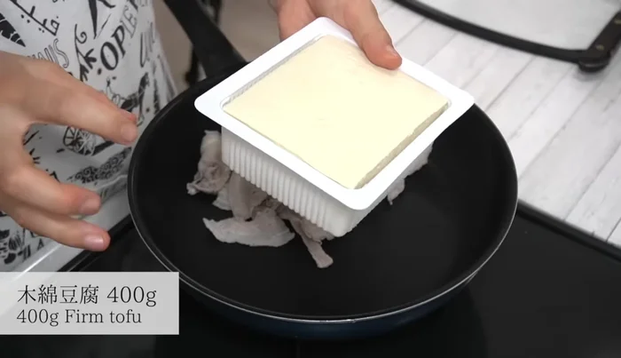 Arrange ingredients in the pan: Add the pork belly, tofu, shirataki noodles, and green onions.