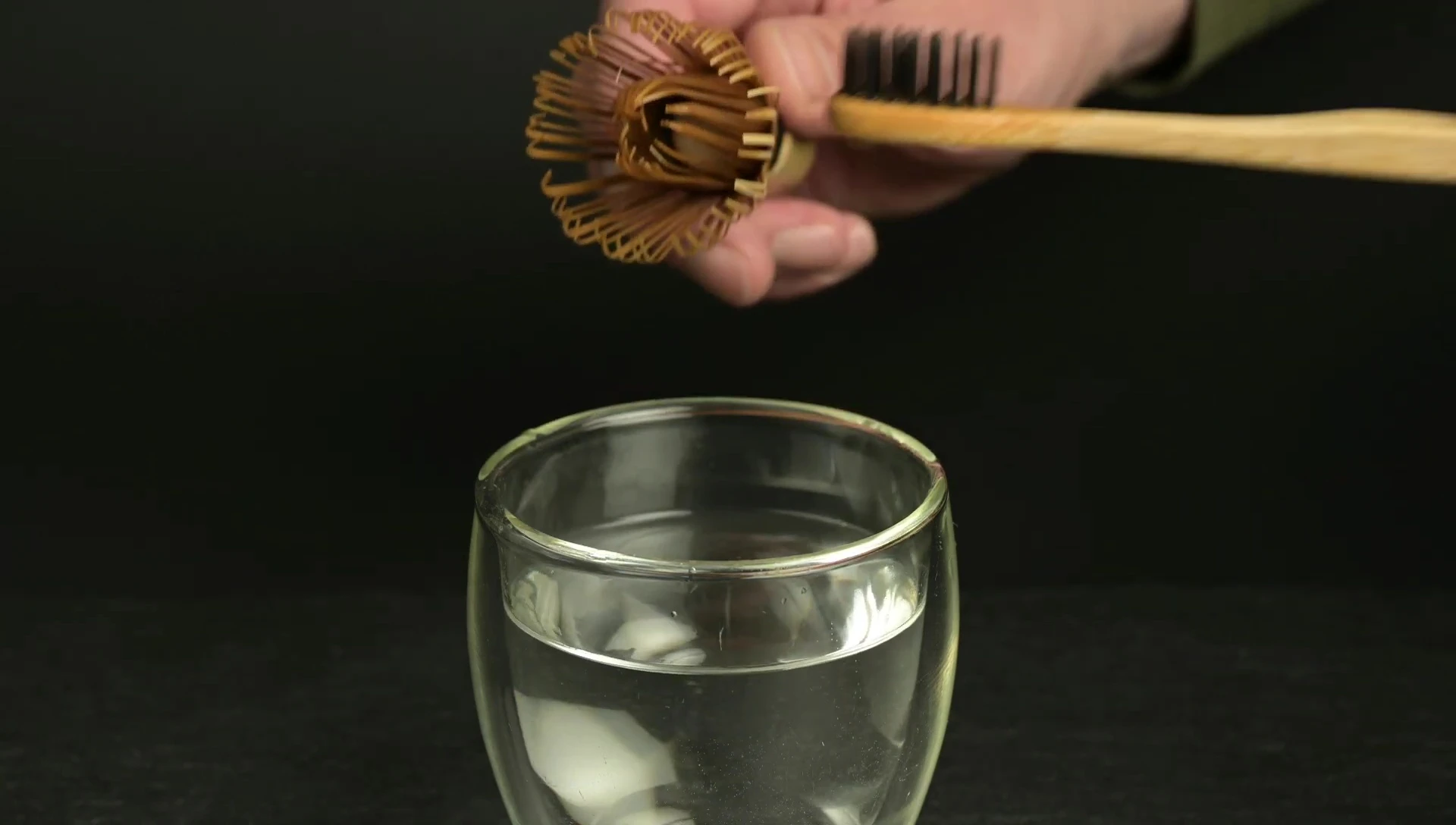 Cleaning matcha whisk with brush and water.
