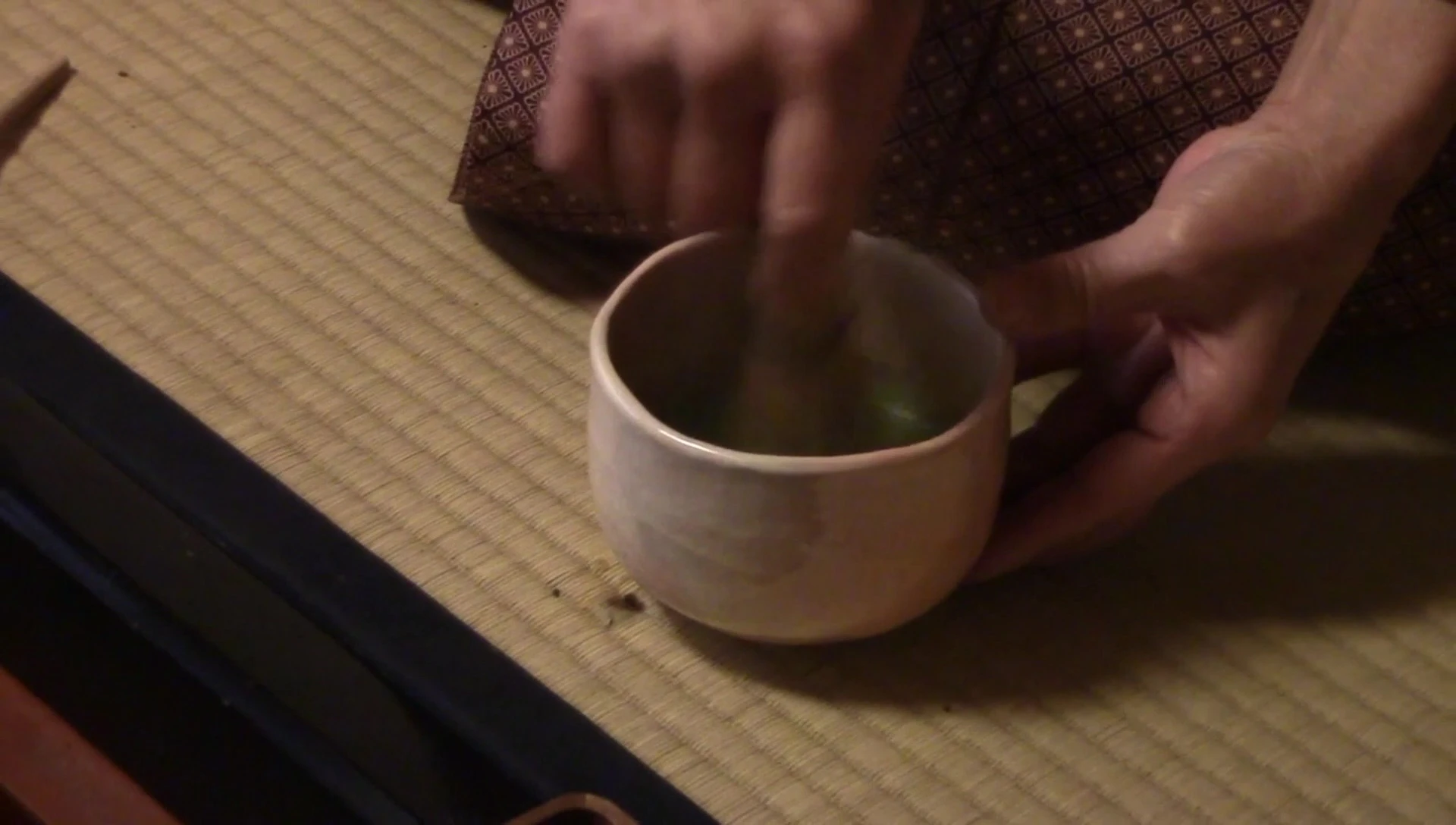 Hands whisking matcha in a bowl