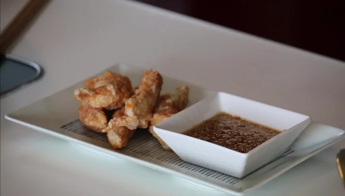 Serve chicken with sesame sauce and garnish with some greens.