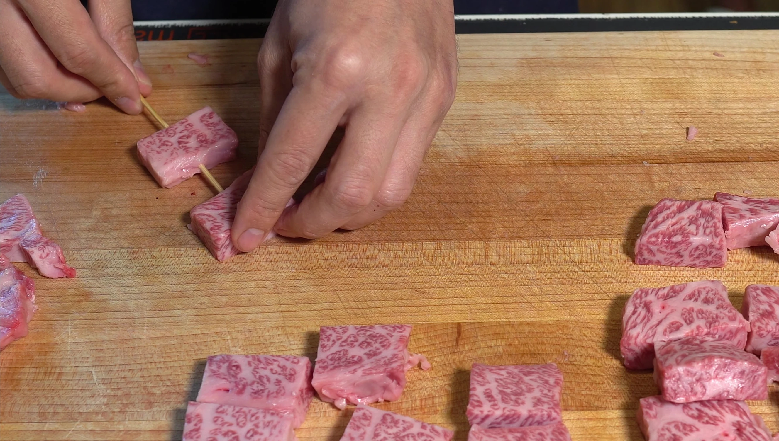 Wagyu beef cubes being skewered for yakitori.