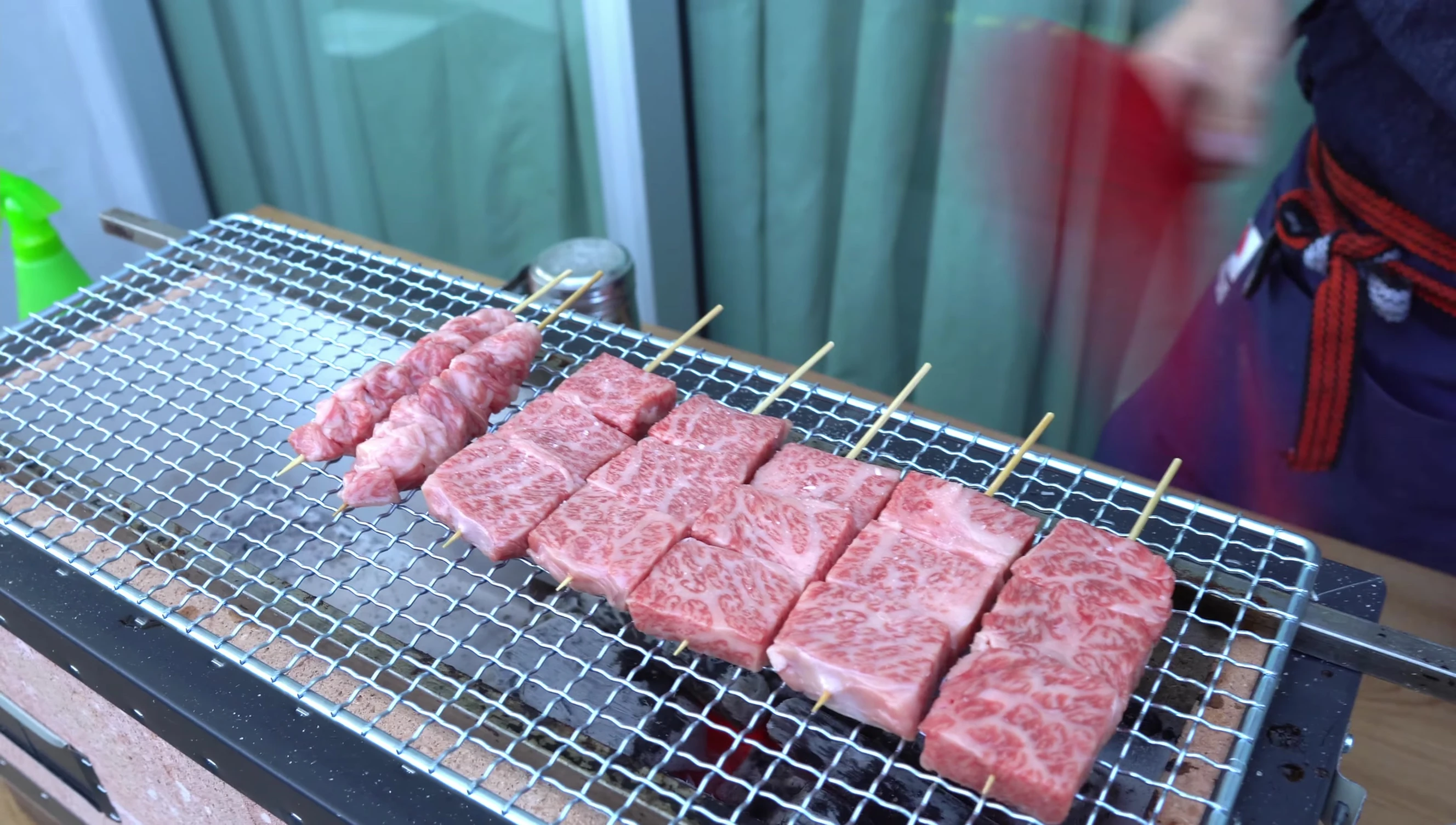 Wagyu beef skewers grilling on mesh grill