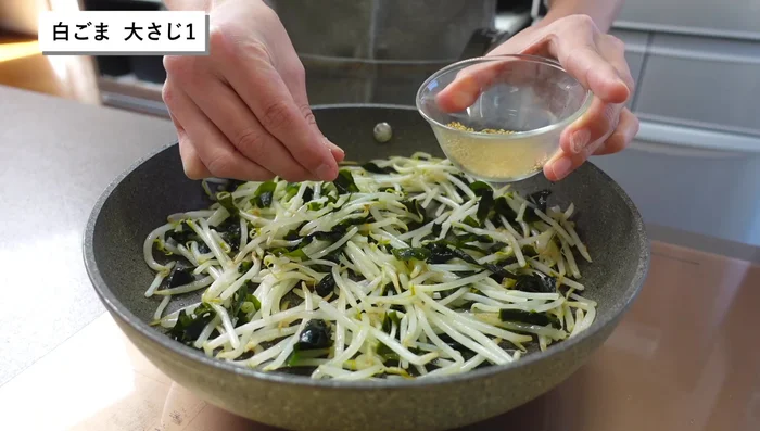 Crush white sesame seeds with your fingertips to release aroma and sprinkle over the bean sprouts.