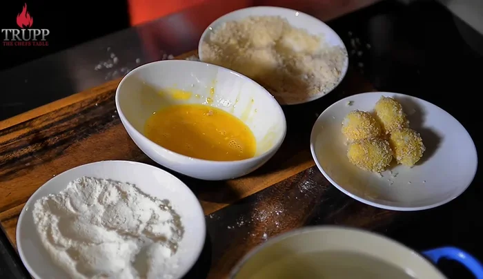 Roll the egg-washed eggs in breadcrumbs.
