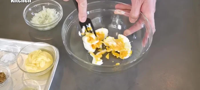 Mash the boiled eggs with a fork.
