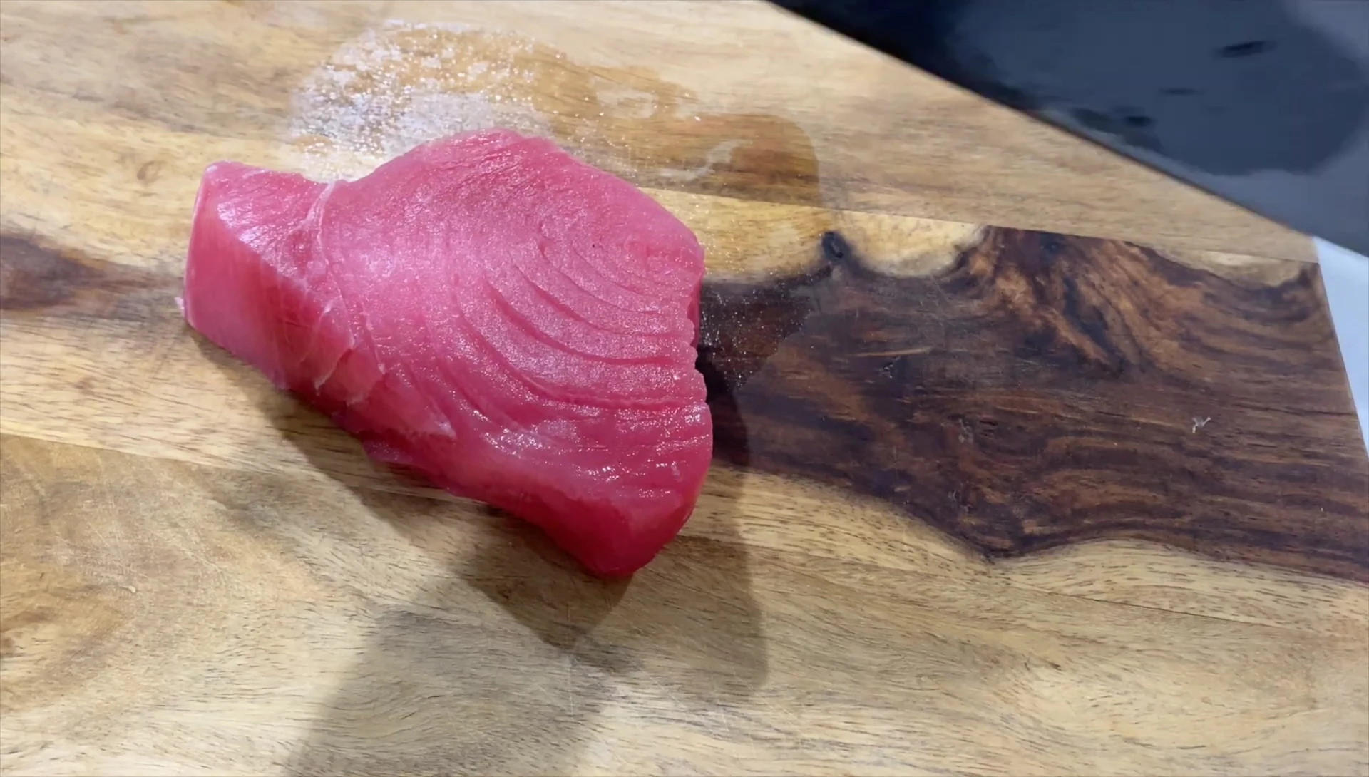 The chef is examining the tuna before preparing to cut it.
