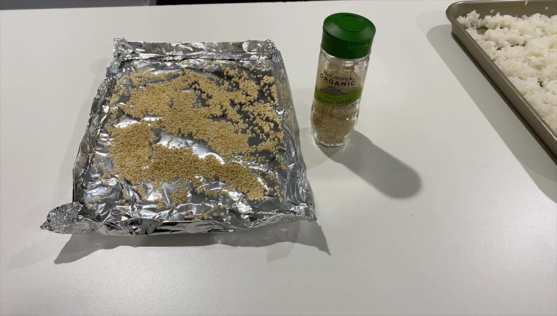 Sesame seeds being placed in a small aluminum foil container before being toasted in the oven.