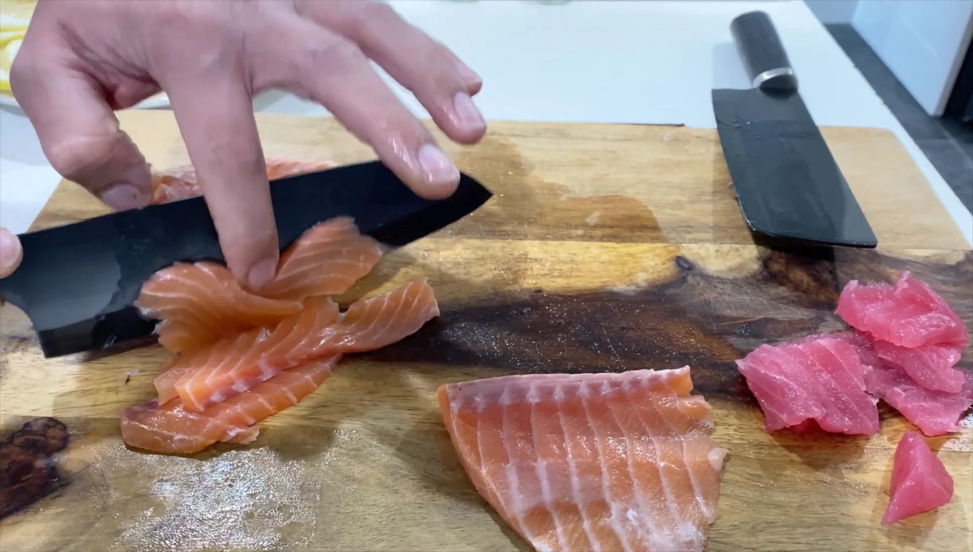 The chef is attempting a precise cut of a fish fillet.