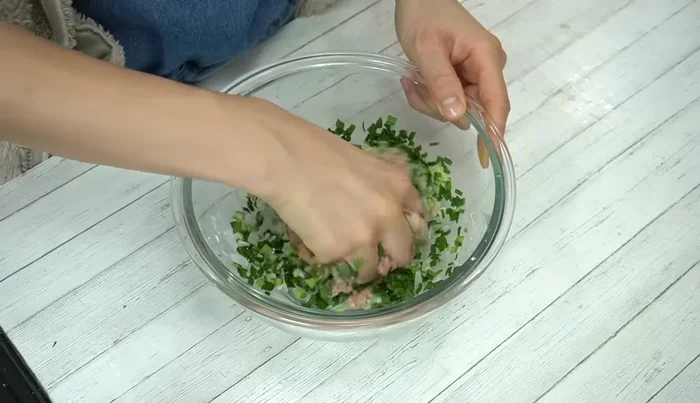 Add chopped green onions and chives to the meat mixture. Gently mix in the prepared daikon radish slices, being careful not to crush them.