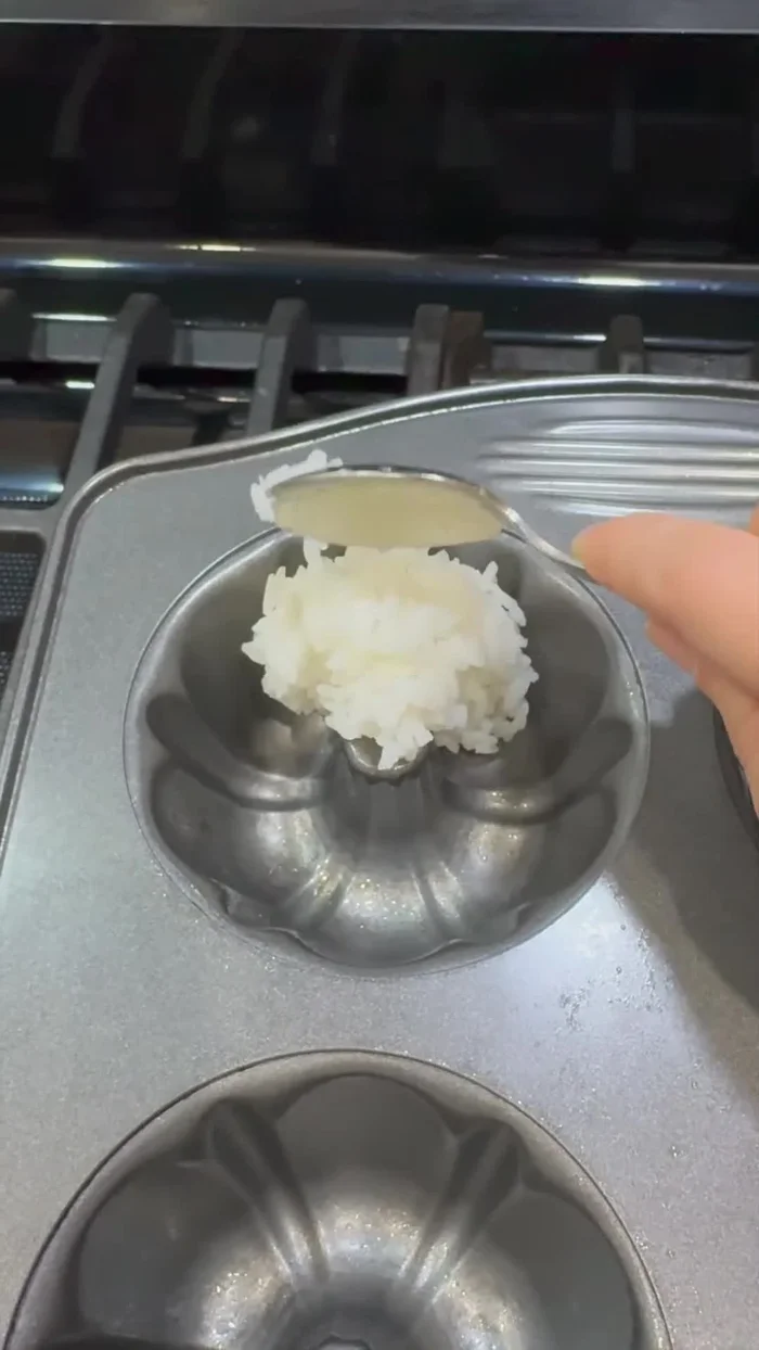 Fill a mini buttcake mold 1/3 full with sushi rice and press down.
