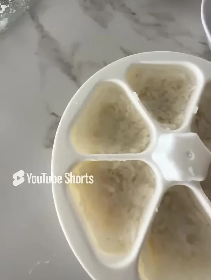 Wet the onigiri mold with water. Fill the mold with rice, wetting your finger to prevent sticking. Create a well in the center for the filling. Ensure the filling doesn't touch the sides.