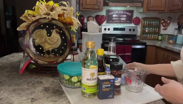 In a measuring cup, combine 1/4 cup rice wine vinegar, 1 tablespoon sesame oil, 1 tablespoon soy sauce, and red pepper flakes to taste.