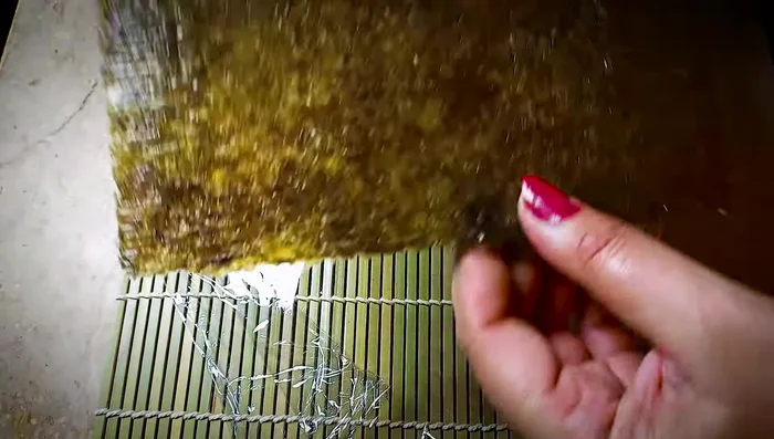 Place a polythene sheet on a bamboo rolling mat. Place a nori sheet shiny side up.