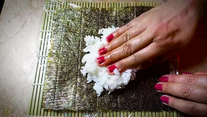 Spread some rice onto the nori sheet. Sprinkle with toasted sesame seeds.