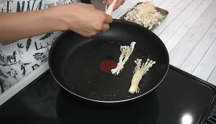 Add the enoki mushrooms to the pan and press down with a spatula to cook, ensuring even browning. Flip and repeat.