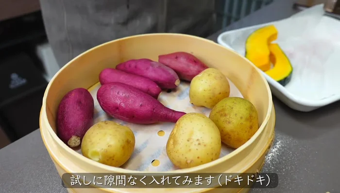 Prepare your ingredients: new potatoes, pumpkin, bread, and sausages. Arrange them in the Seiro, using a sheet for easy cleaning and to prevent sticking.