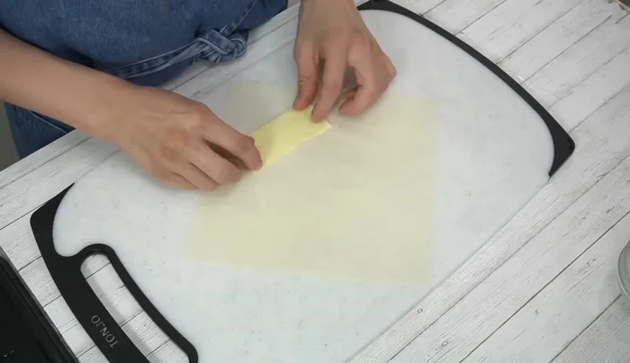 Assemble spring rolls: Place sliced cheese, chicken, and umeboshi mixture on the rough side of a spring roll wrapper. Fold in the sides, add shiso leaves, and roll tightly, sealing with the flour paste (305.96)