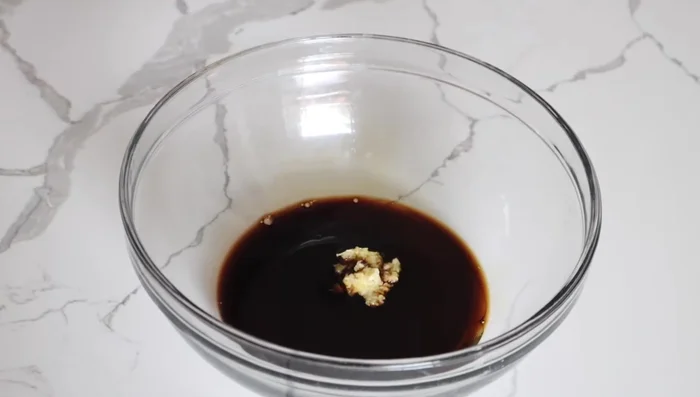 Once cooled, transfer the sauce to a bowl. Add sesame oil, grated garlic, and sesame seeds. Mix well.