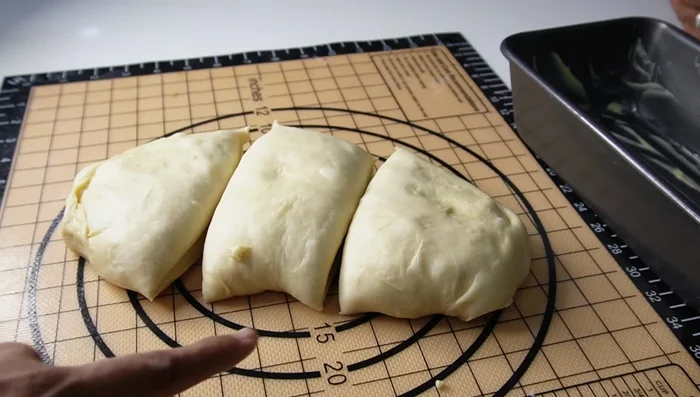 Shape the dough: Grease a loaf pan. Divide the risen dough into three equal parts. Shape each part into a log, then flatten and roll it into a longer log.