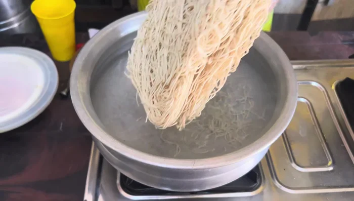 Boil the noodles in a kadai until cooked. Set aside.